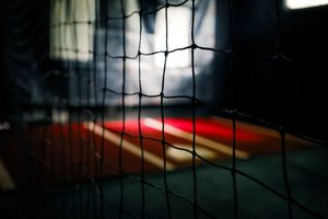 A sports net silhouetted against dark background with dramatic lighting creates moody athletic atmosphere.