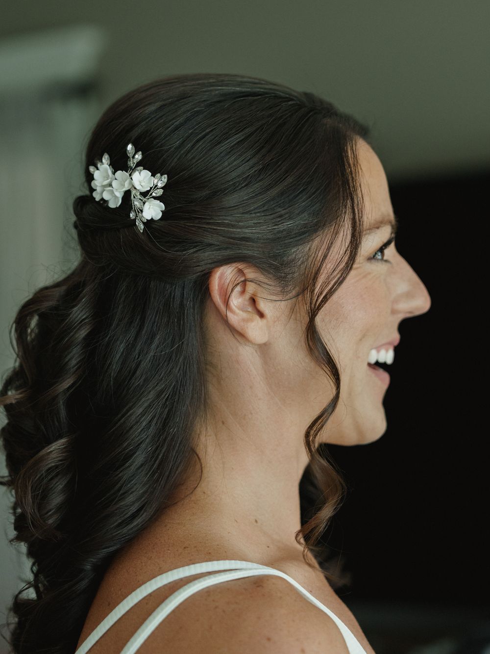 Elegant bridal hairstyle with floral hair accessory and soft curls.