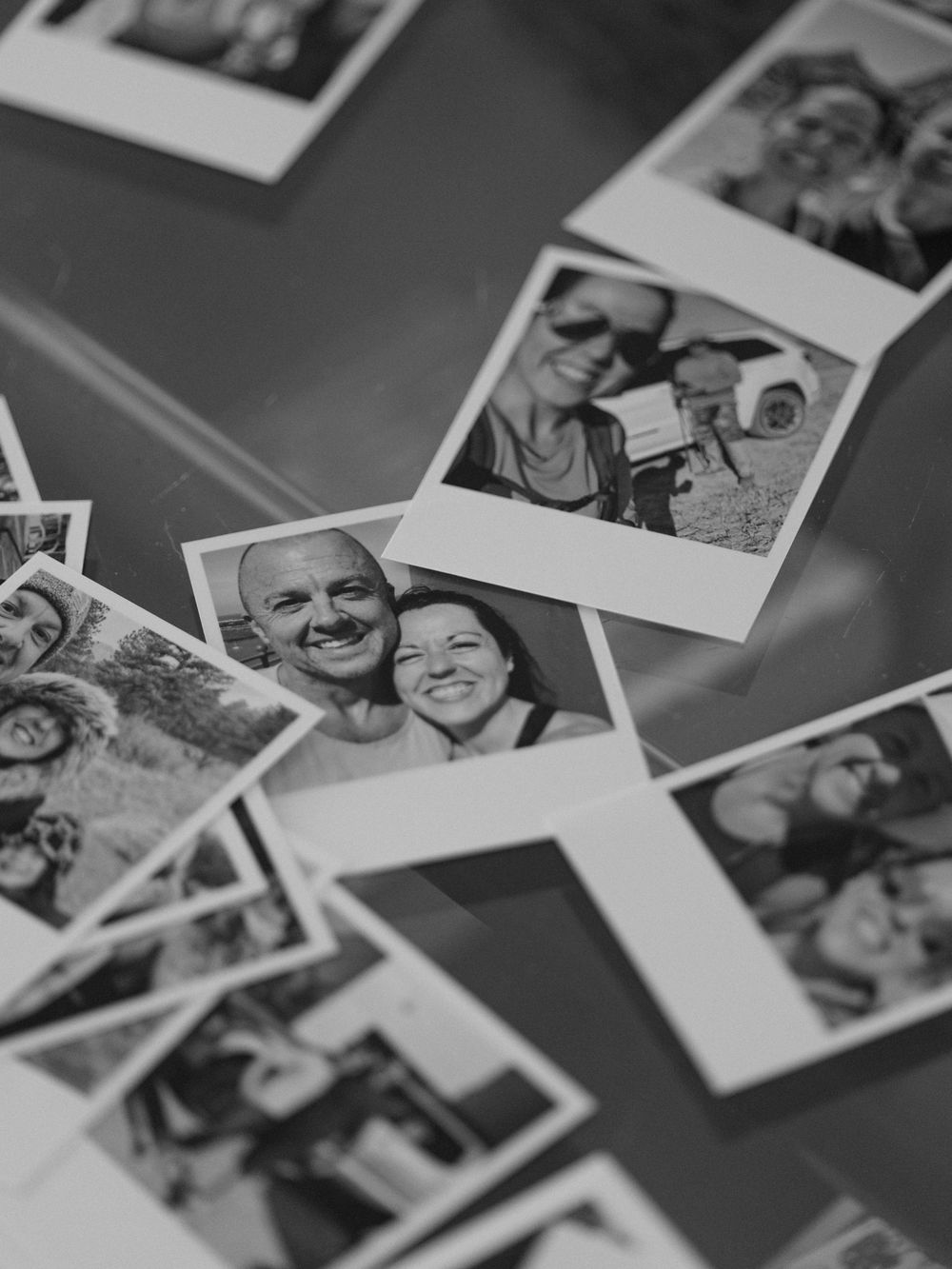 Collection of black and white polaroid photographs arranged on dark surface.
