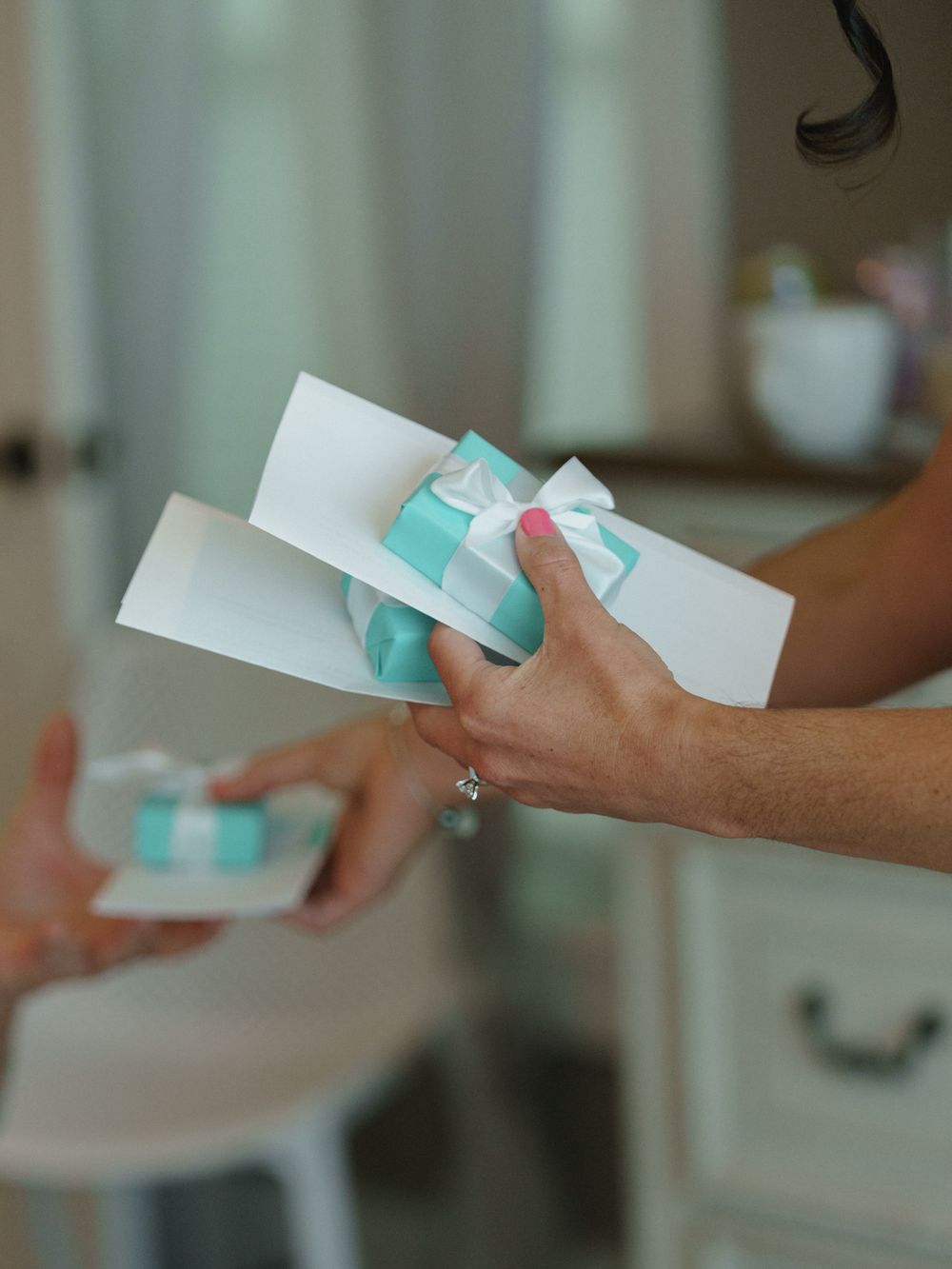 Hands passing small mint-colored envelopes in sequence against a blurred background.