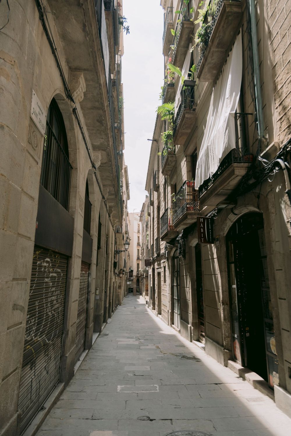 Narrow cobblestone alley in Barcelona Gothic Quarter with tall stone buildings.