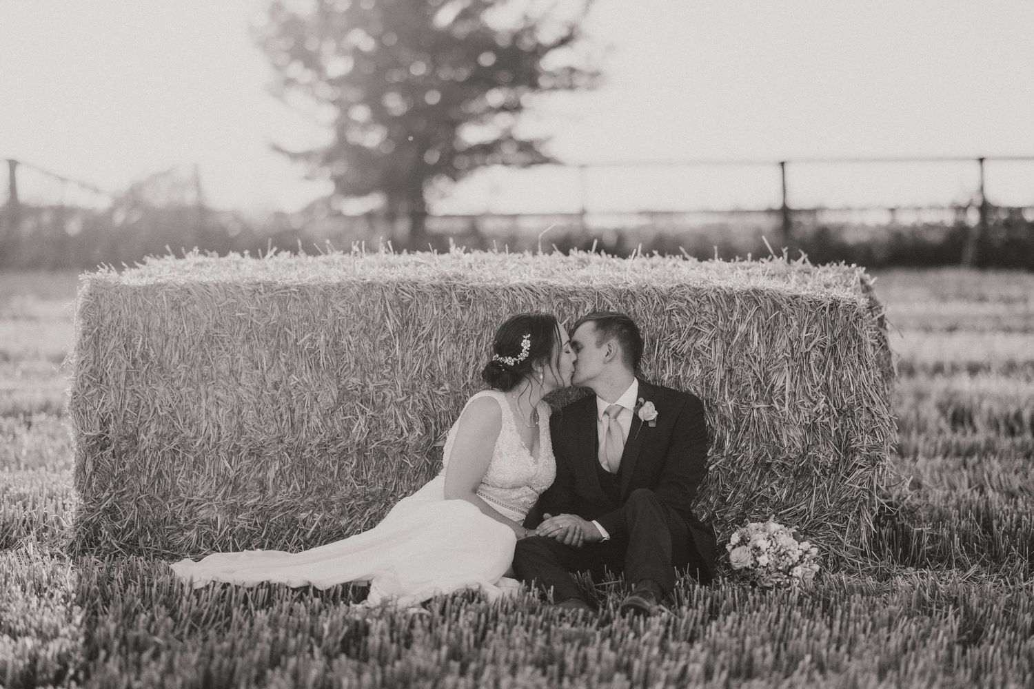 A black and white panoramic photo series shows a couple laying together in a tall grass field.
