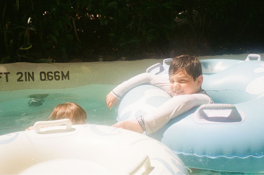 Kids splash and play in a backyard swimming pool on a sunny summer day.