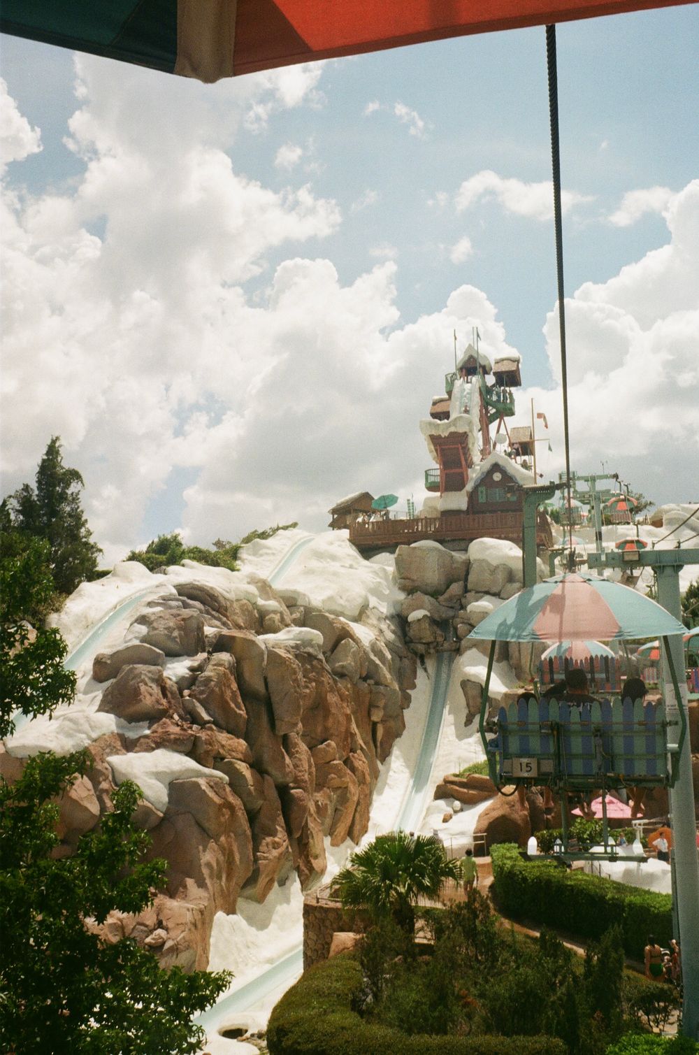 View of Disney's Blizzard Beach water park showing snowy peaks and water slides surrounded by lush greenery against blue sky.