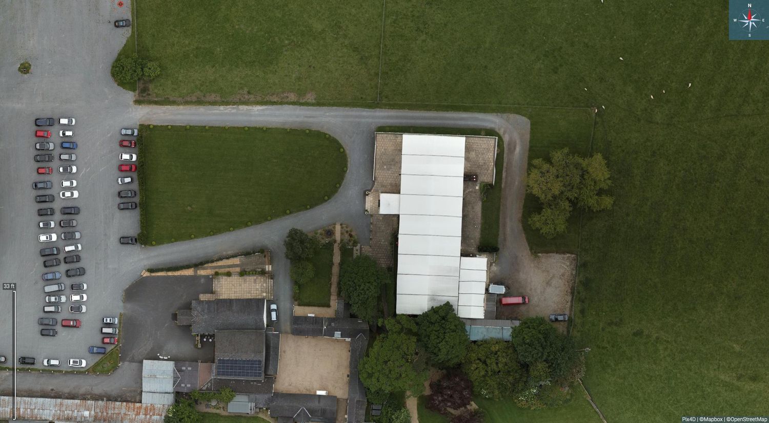 Aerial view of a white storage facility building with adjacent parking lot and grassy areas.