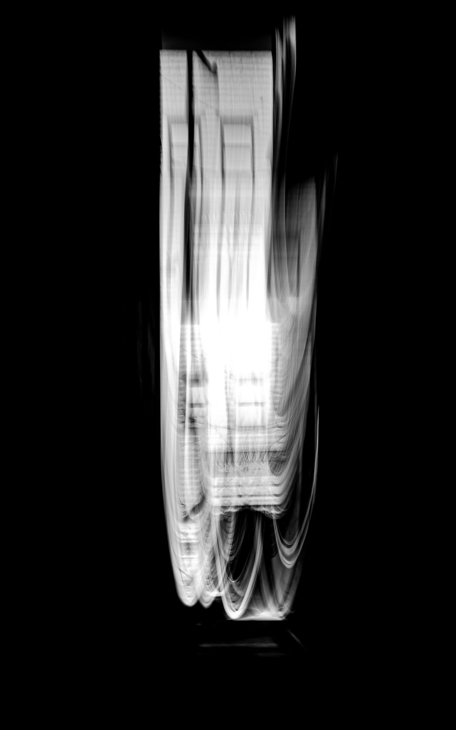 Minimalist black and white photograph of curtains illuminated by window light.