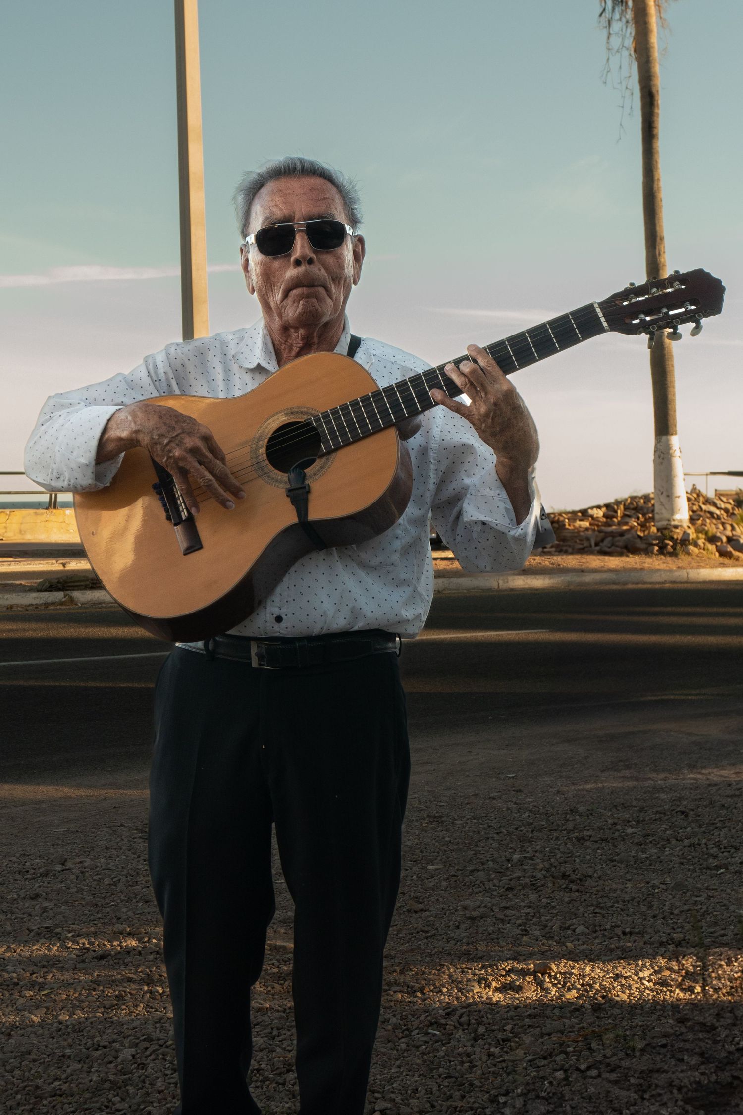 Musician playing acoustic guitar outdoors during golden hour.