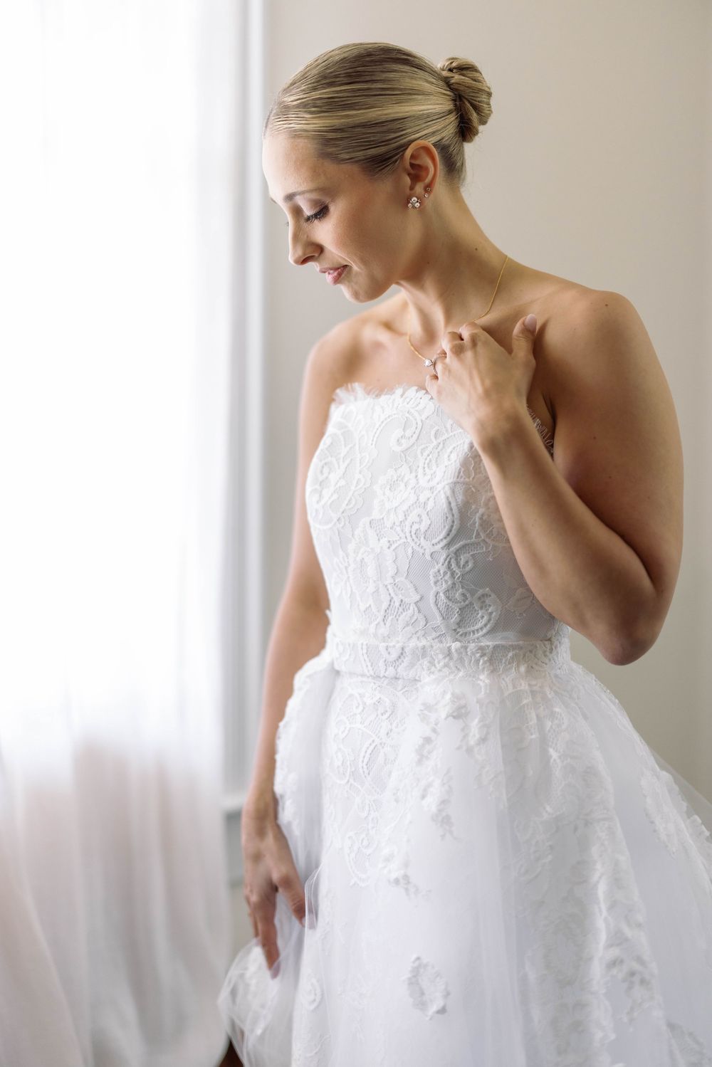 Elegant white lace wedding gown with strapless neckline and delicate floral appliques shown in soft natural light.