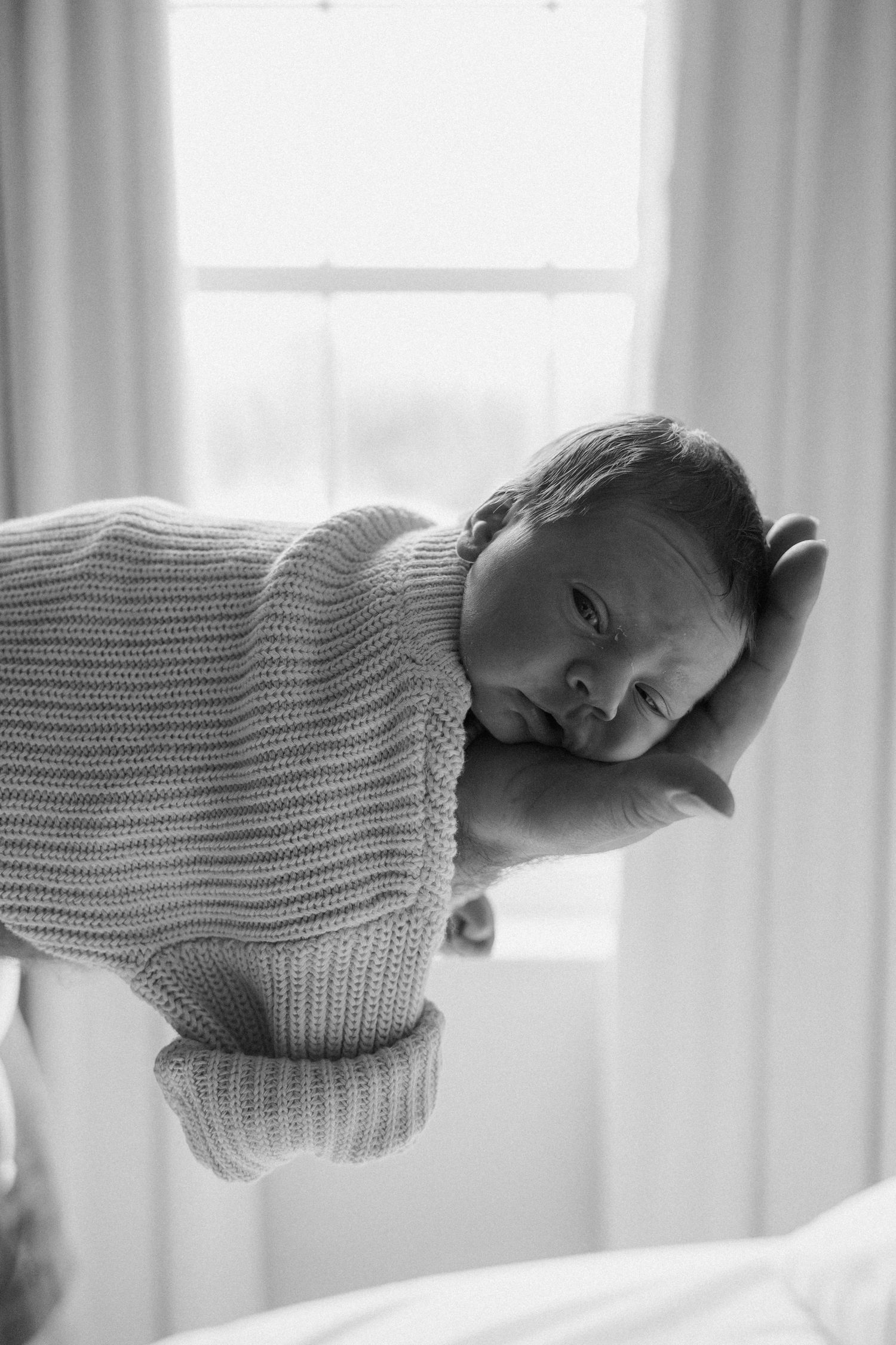 A series of black and white portraits showing the same person looking melancholy while wearing a chunky knit sweater.