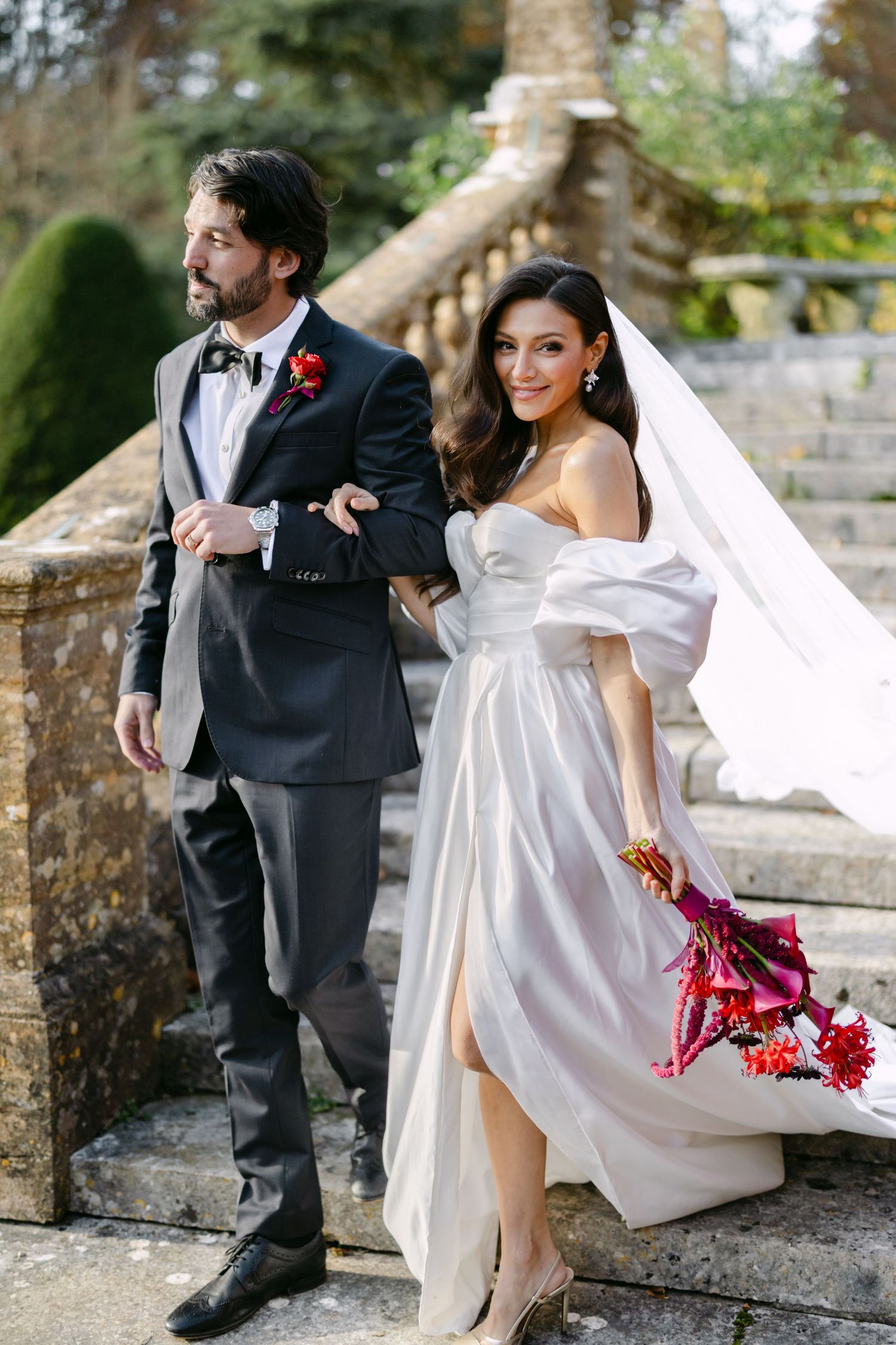 Romantic wedding photos featuring white gown with flowing veil against stone architecture.
