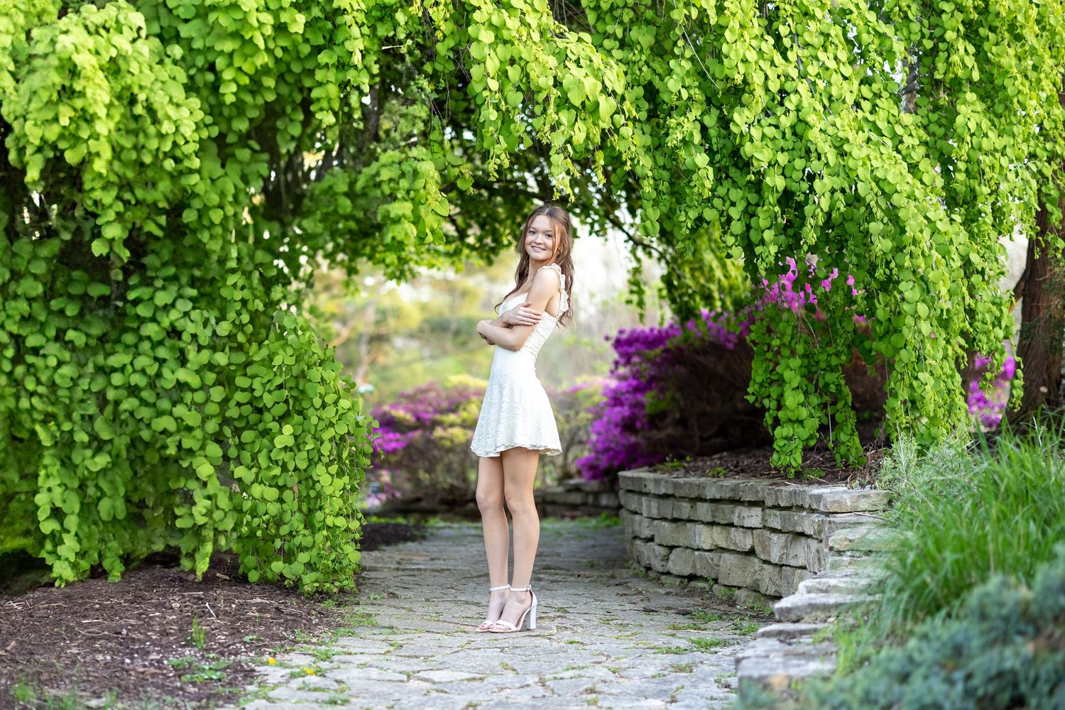 Springfield, IL senior photographer captures a senior surrounded by trees with large green leaves during a session in Central, IL