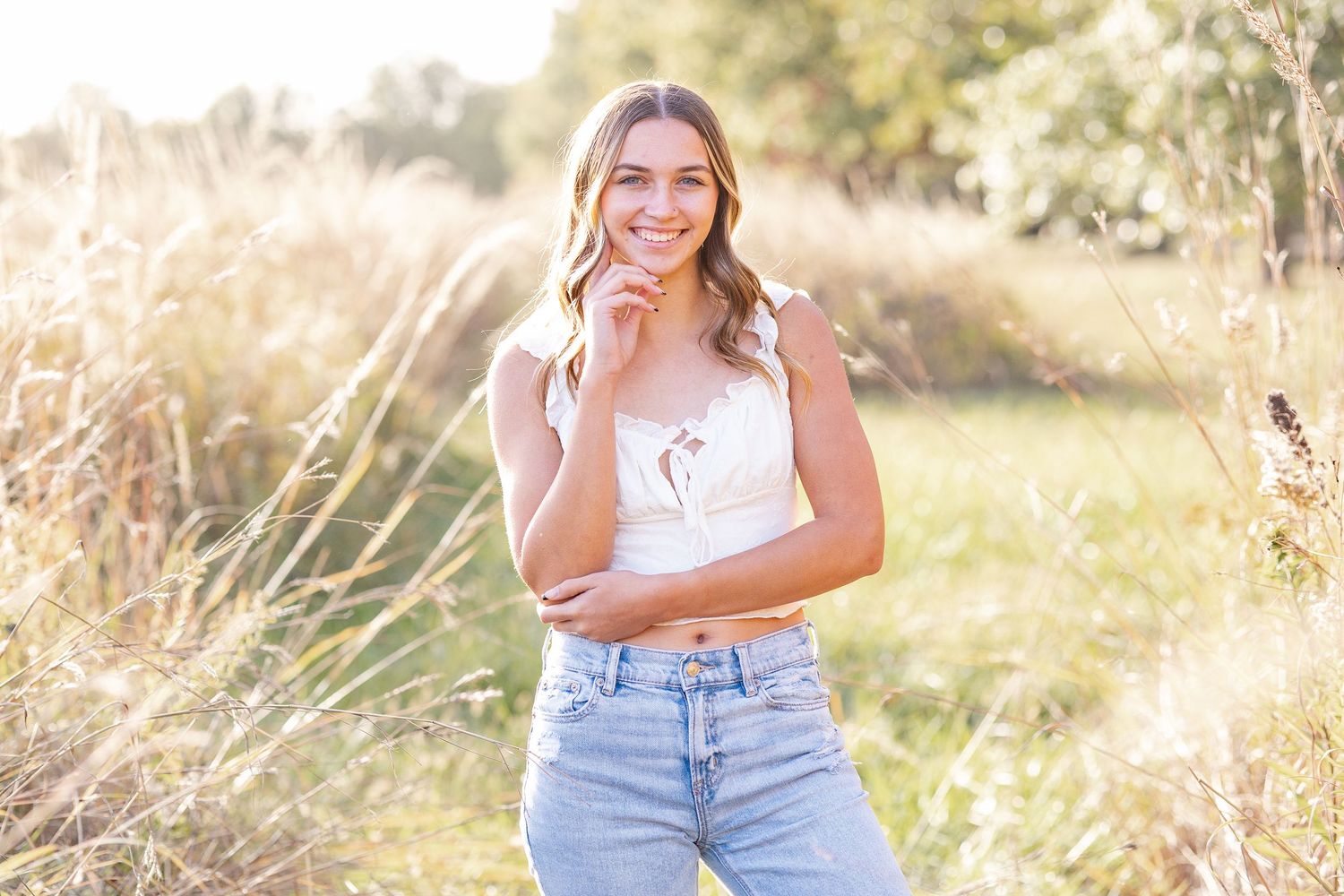 Springfield, IL senior photographer captures a senior in a field of tall grass during a session in Central, IL