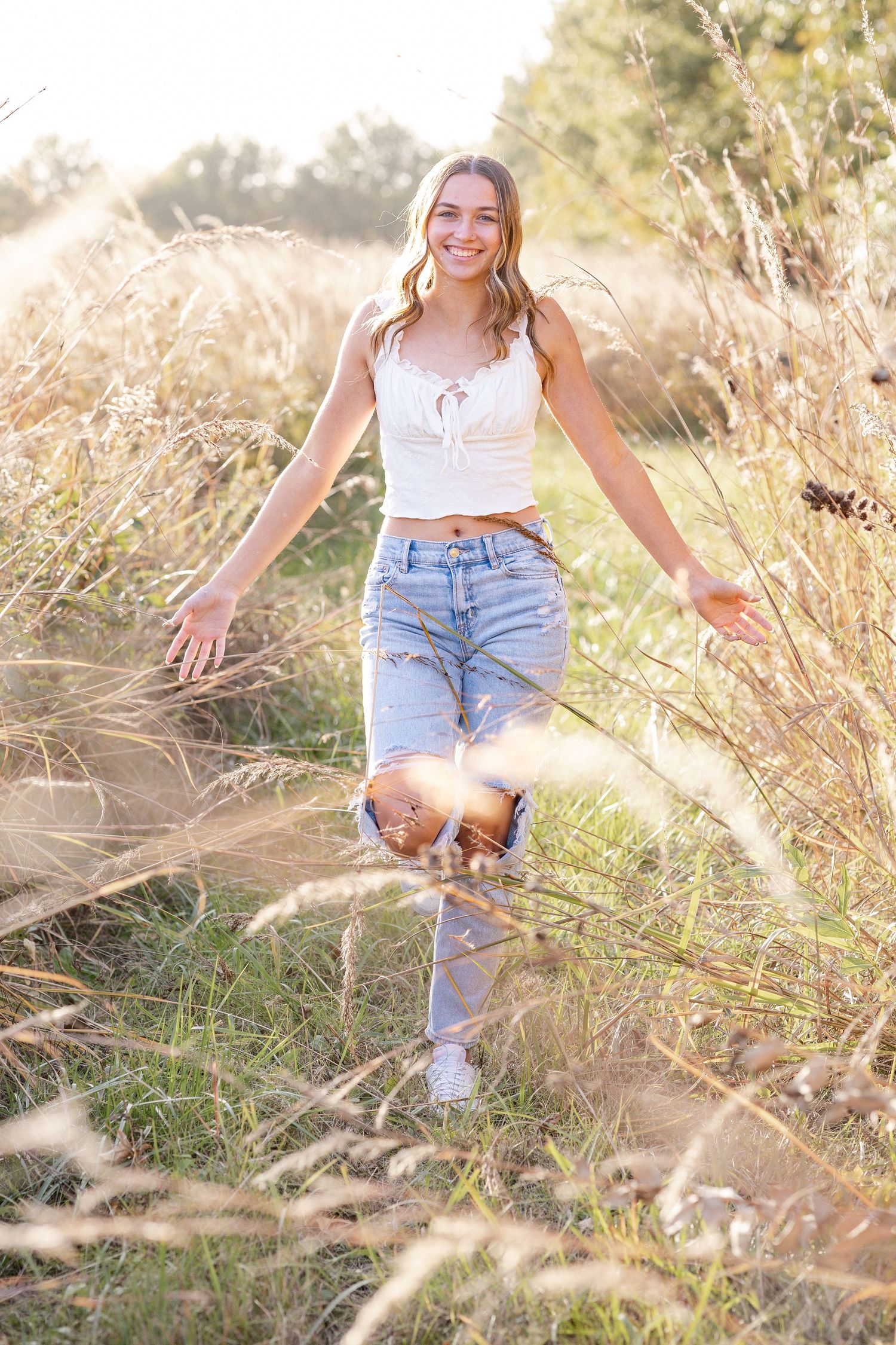 Springfield, IL senior photographer captures a senior walking through tall grass during a session in Central, IL
