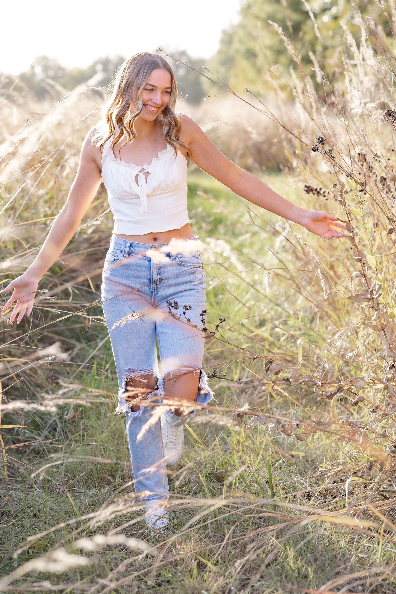 Springfield, IL senior photographer captures a senior walking through fall grass fields during a session in Central, IL