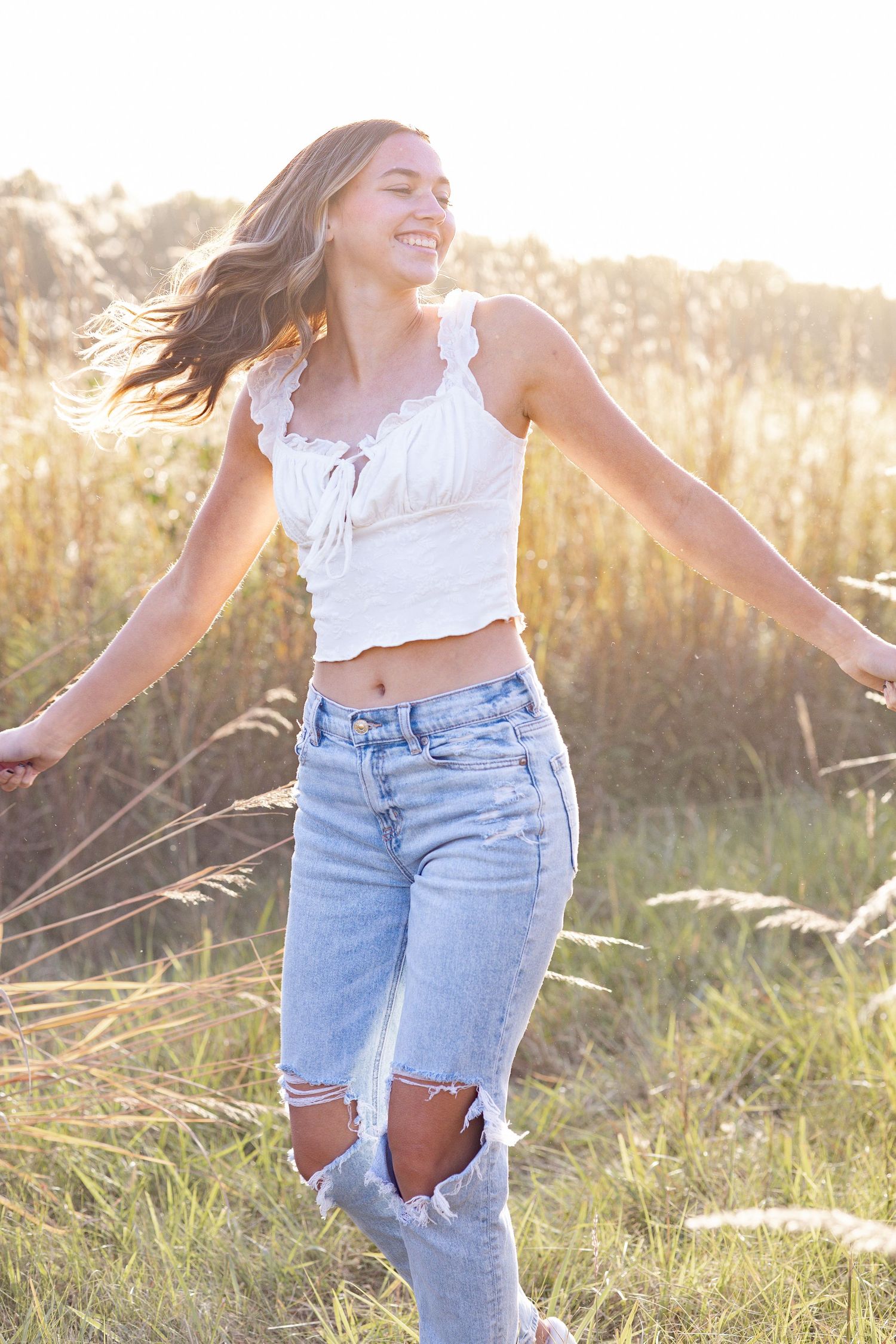 Springfield, IL senior photographer captures a senior spinning amongst tall grass during a session in Central, IL