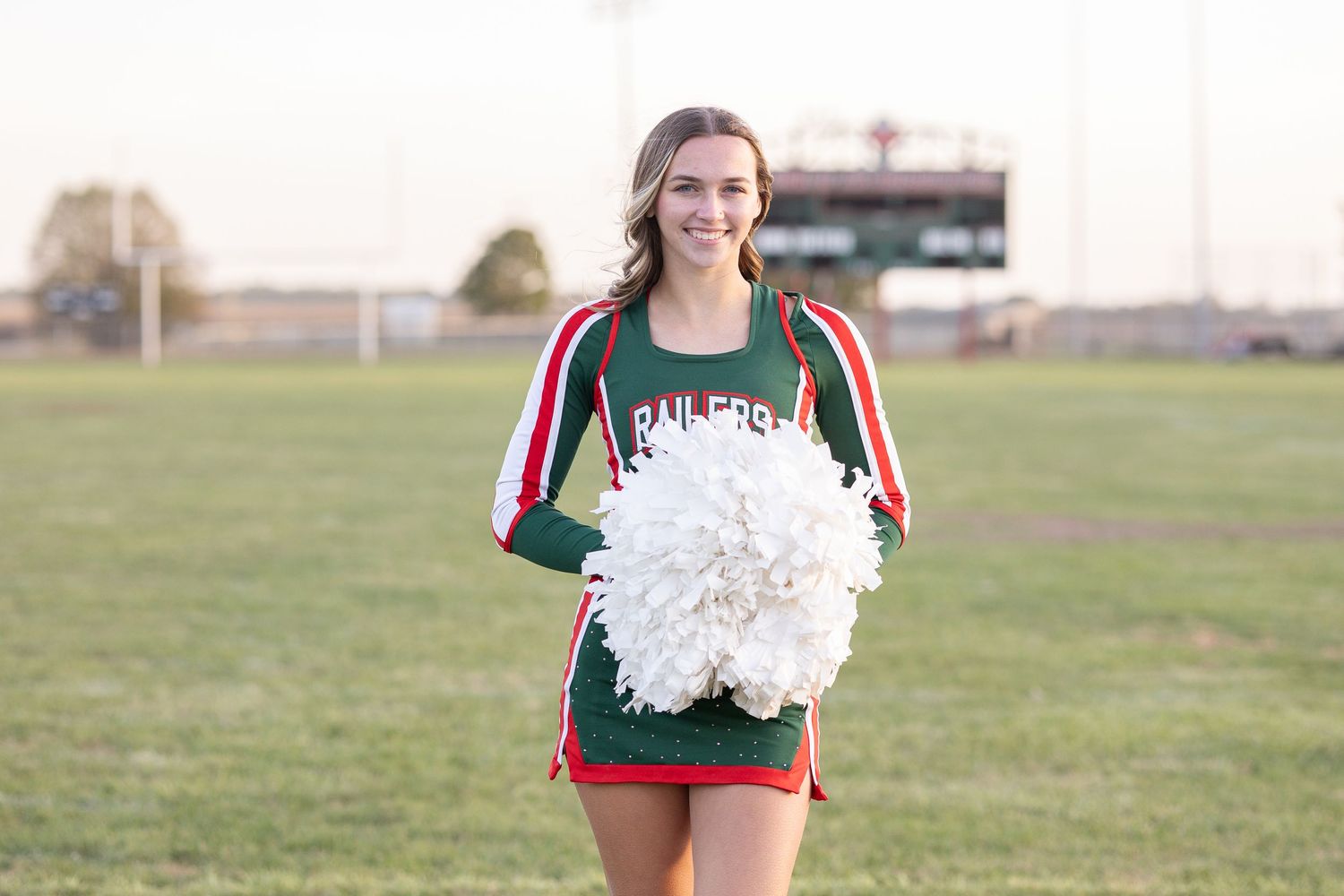 Springfield, IL senior photographer captures a senior in her cheerleading outfit on a football field during a session in Central, IL