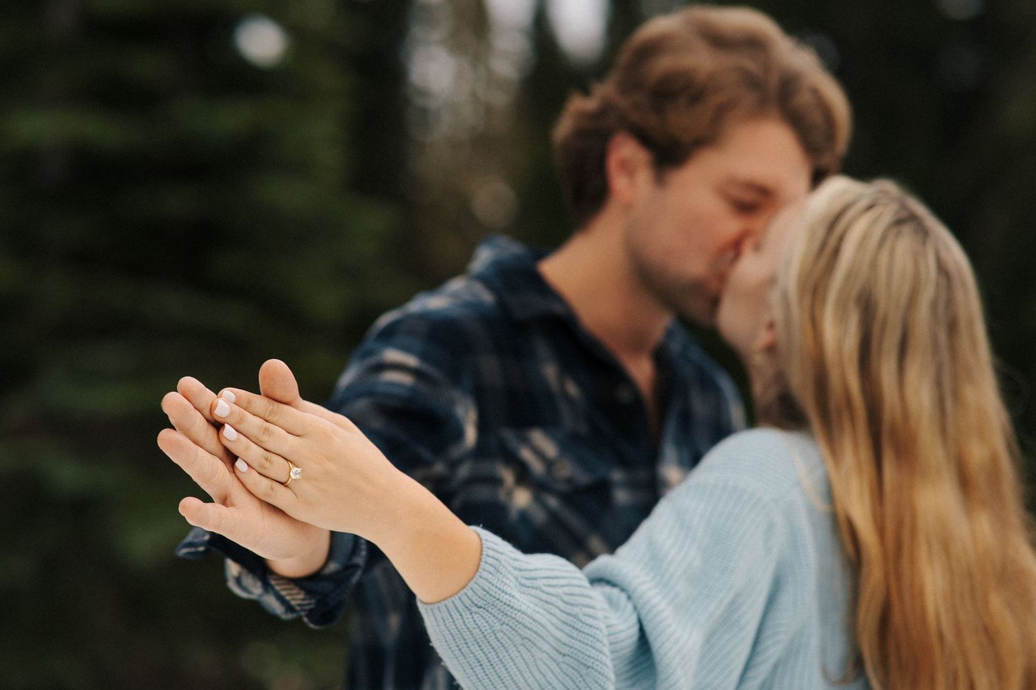 A romantic couple embrace in the forest while soap bubbles float around their intertwined hands in a magical moment.