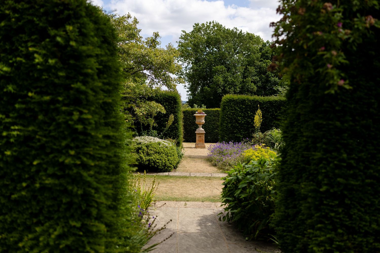 Historic stone manor hotel with classic Georgian architecture and manicured topiary gardens along entrance path.