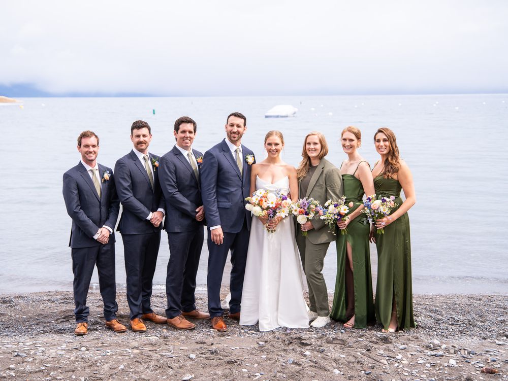 Wedding party group photo on Lake Superior shore with mossy green and charcoal gray color theme.