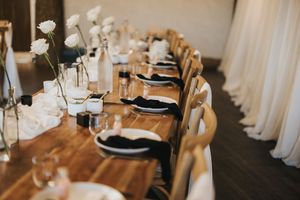 An elegant table setting with gold chargers, black plates, and white linens in a banquet hall at Grand Lodge Oaklands.