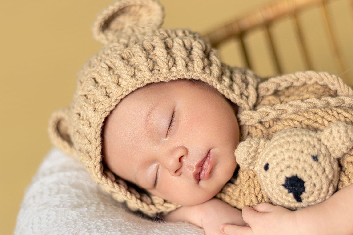 Newborn photography setup with beige knit wrap and neutral backdrop.