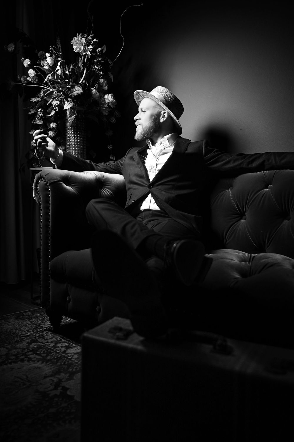 Artistic black and white photograph of a person reclining on a couch in dramatic lighting.