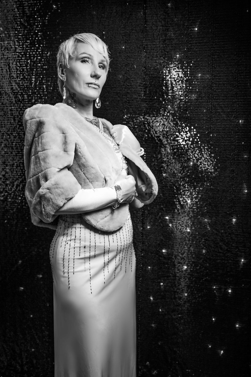 A sequence of dramatic black and white glamour shots shows a figure posing in an elegant white dress against a sparkly backdrop.