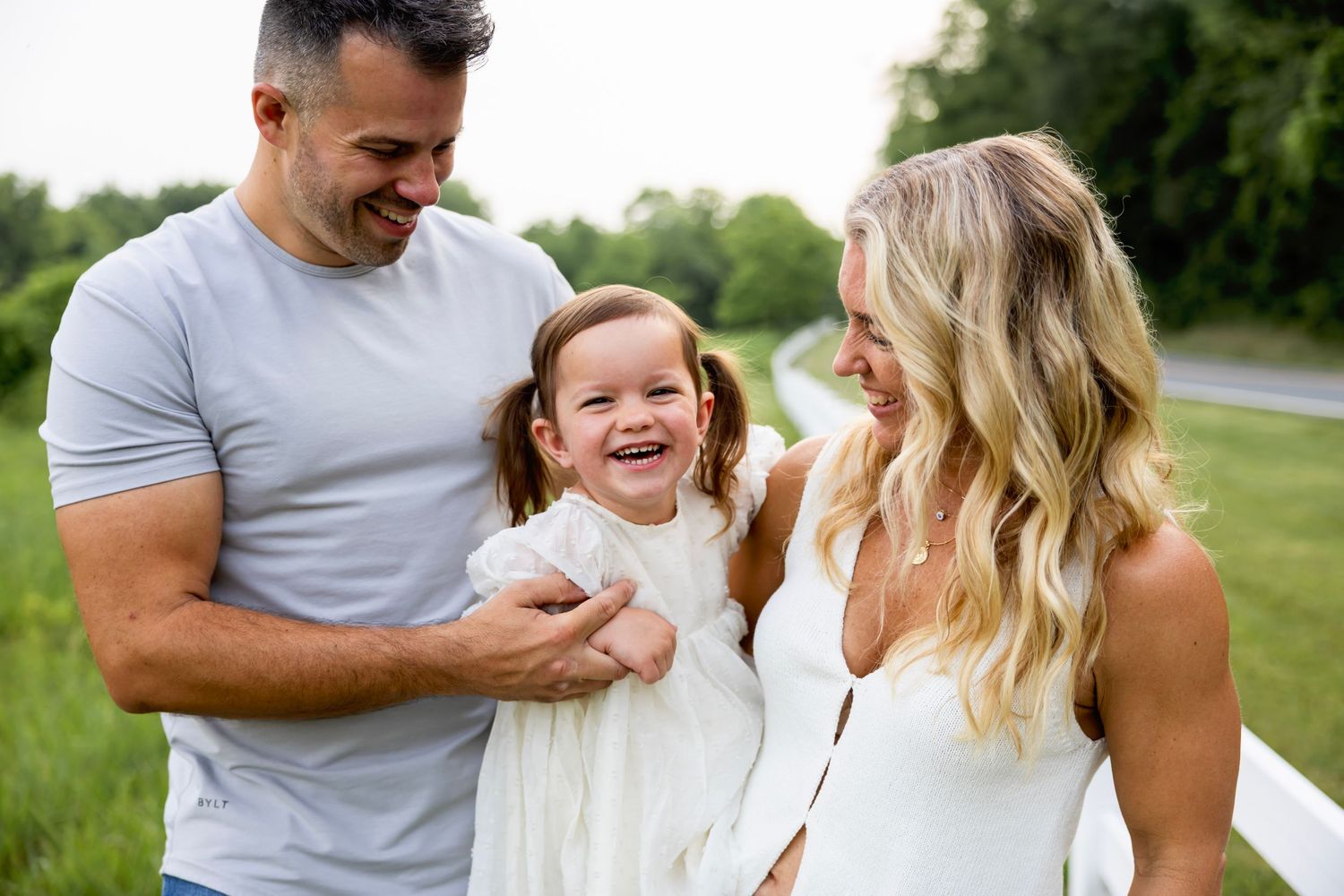 A happy family shares a joyful moment together outdoors on a sunny day in a grassy setting.