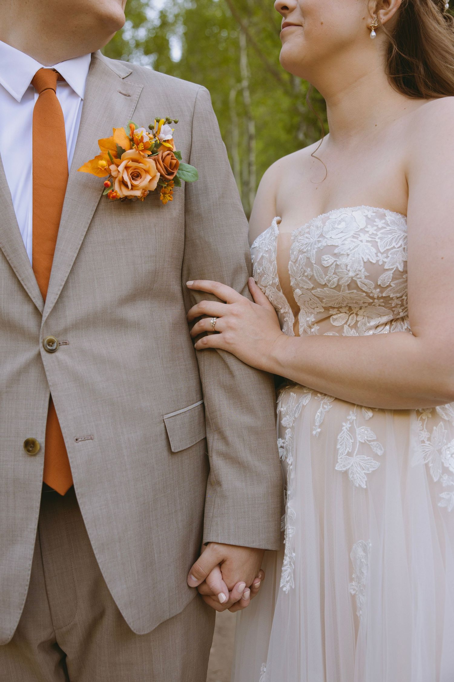 A couple shares an intimate moment along a forest path lined with evergreen trees and birch during a wedding photo session.