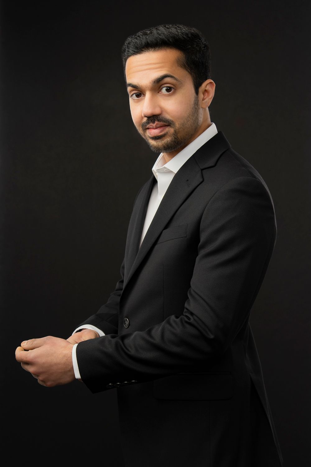 Professional studio portrait against dark background in business attire.