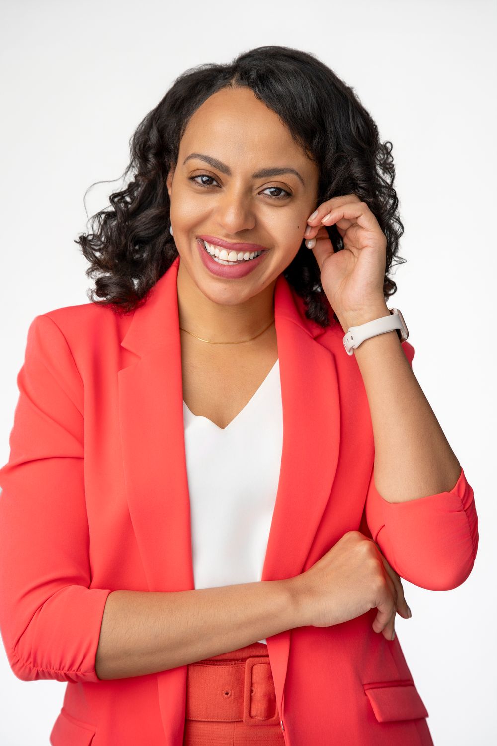 Professional studio portrait showing warm expressions against white background wearing a vibrant coral blazer.