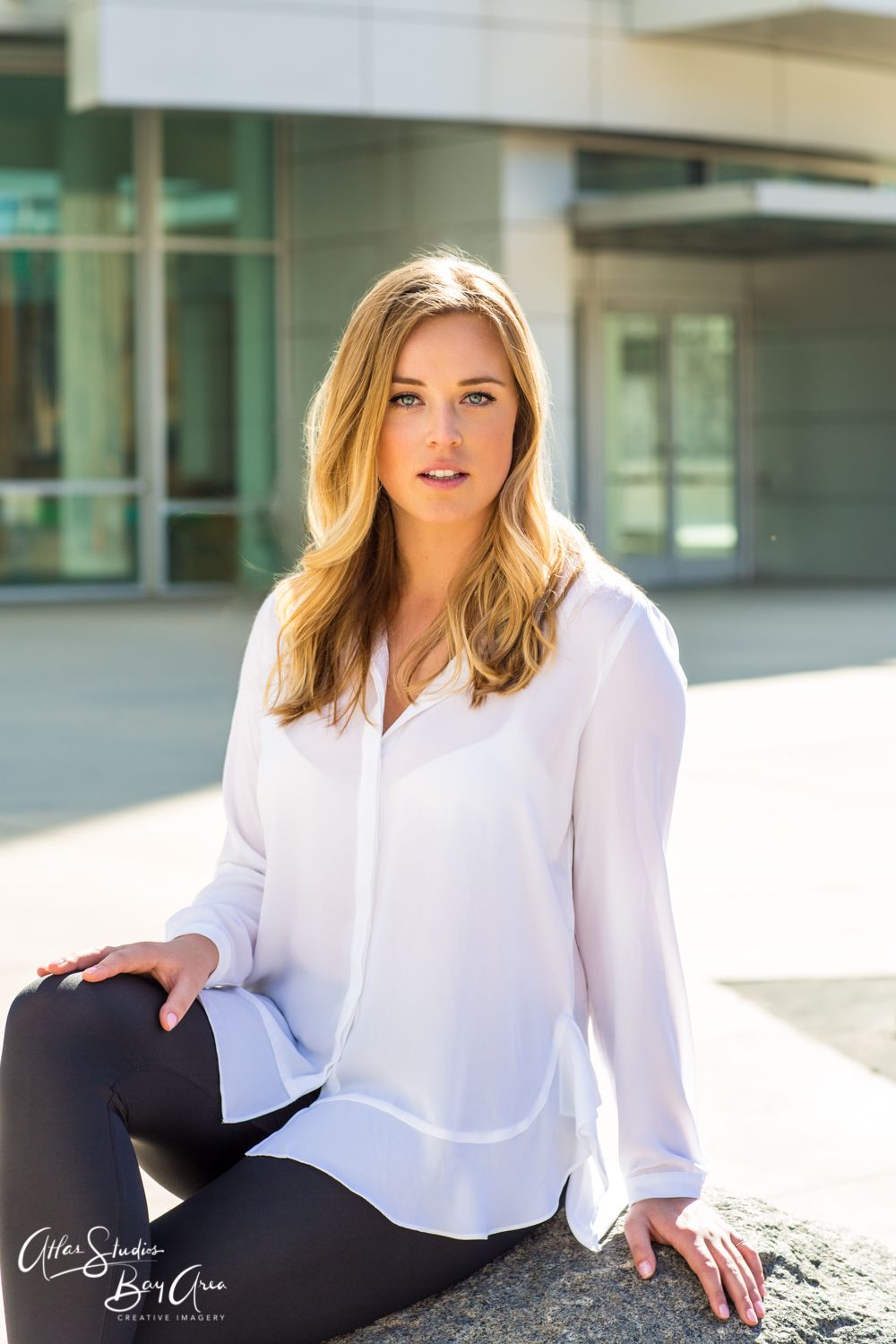 Business professional in white collared shirt and dark pants poses against modern architecture in series of outdoor photos.