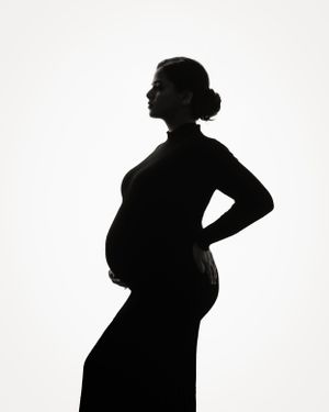 Silhouette of pregnant figure in profile against white background.