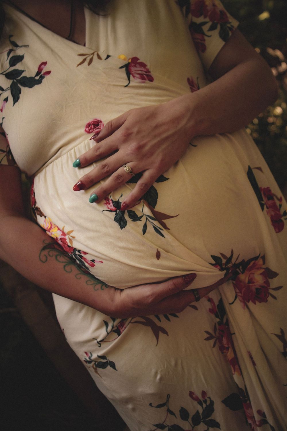 A pregnant woman in a floral dress displays her baby bump with close-up shots of hands caressing her belly.