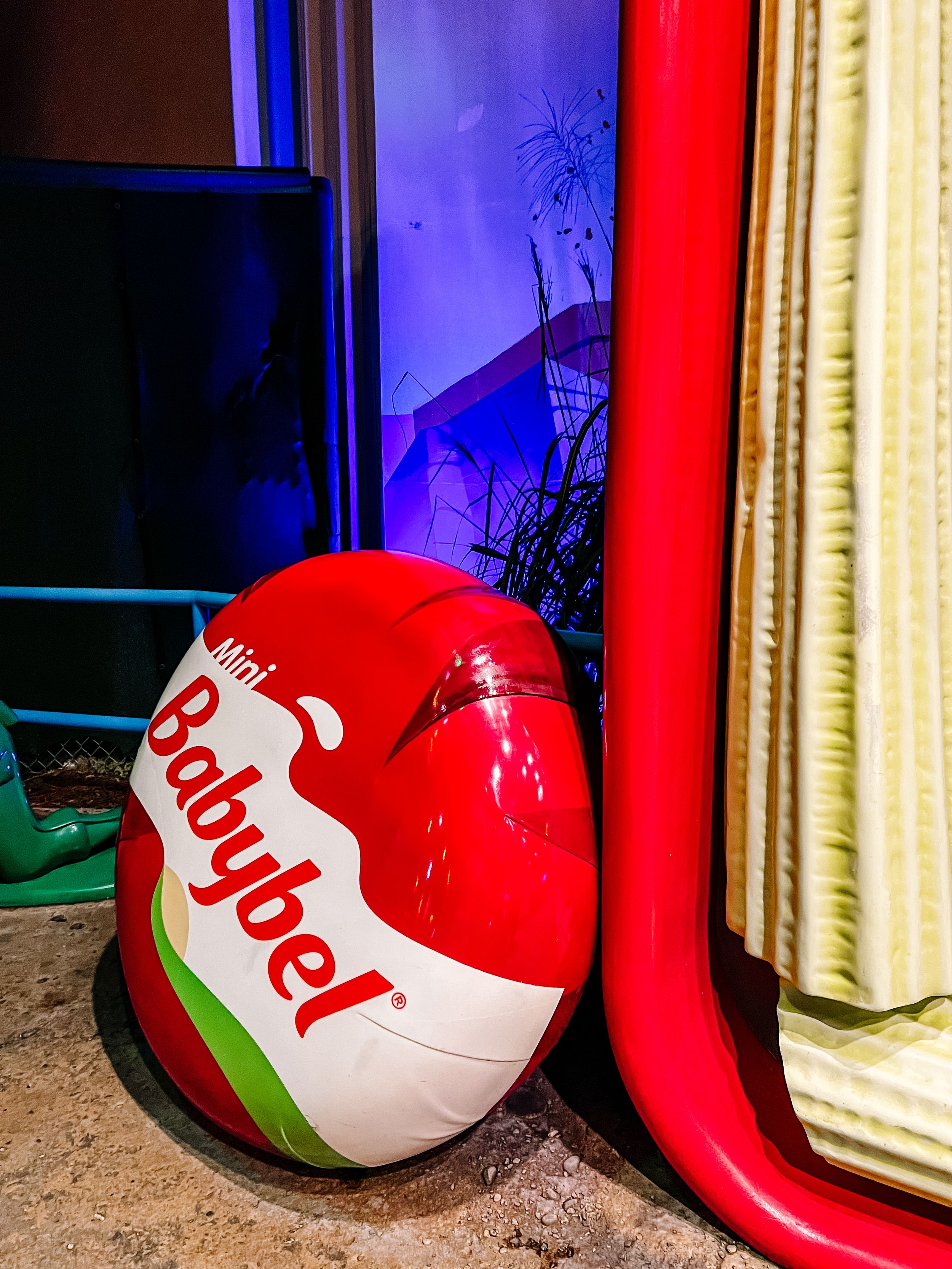 Red and white Babybel cheese prop display with colorful lighting effects.