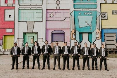Groom and groomsmen pose with a street mural at Hickory Street Annex, a Dallas wedding venue