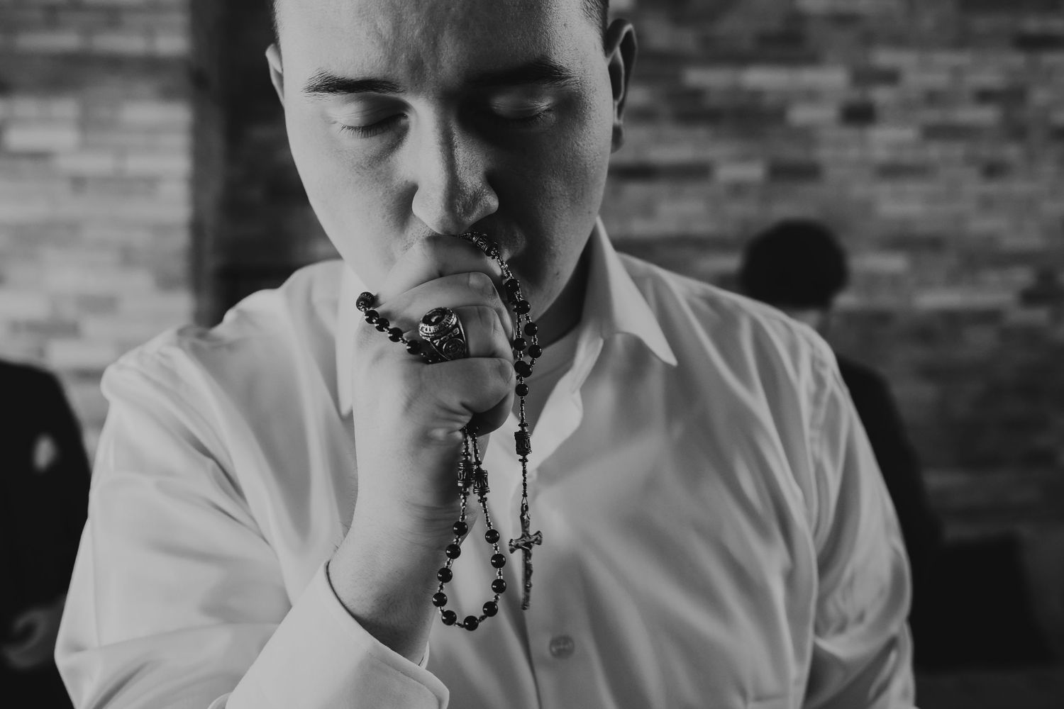 Close-up portrait series shows a person in a white shirt kissing rosary against brick wall.