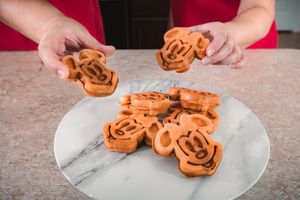 Orange-colored cookies arranged on a white plate against a marble surface.