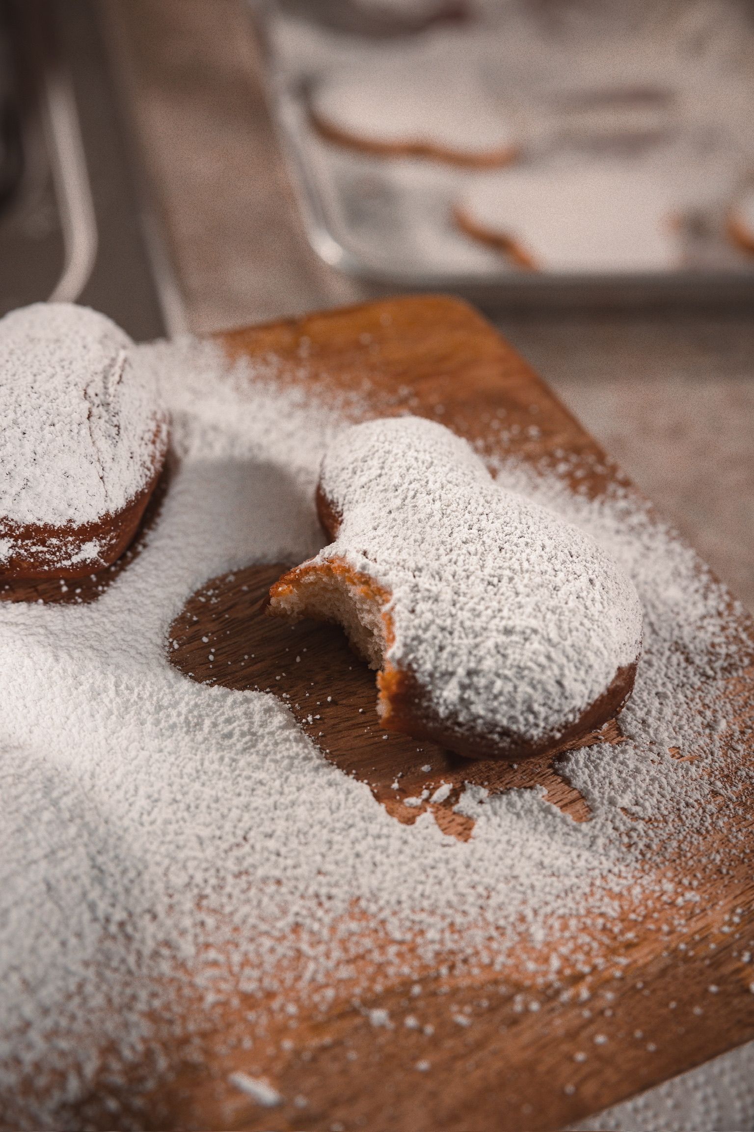Powdered sugar creates a contrast pattern on a wooden cutting board with cookies.