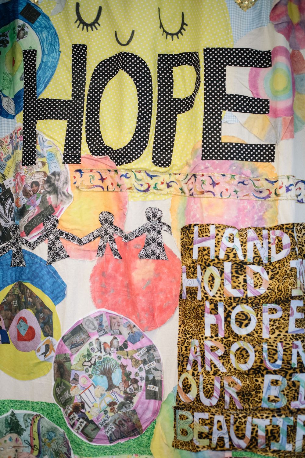 Artistic collage wall featuring colorful text and patterns with words 'Hope' and 'Peace' in glittery letters.