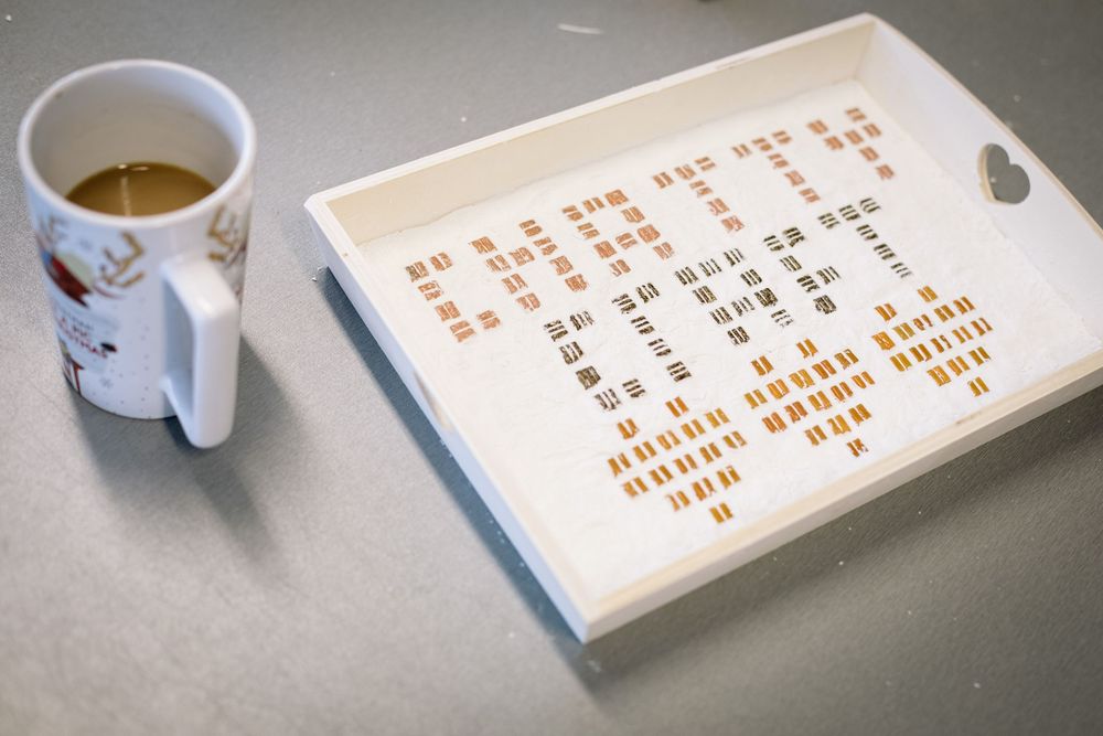 White ceramic mug sits beside an open book with orange text under soft lighting.