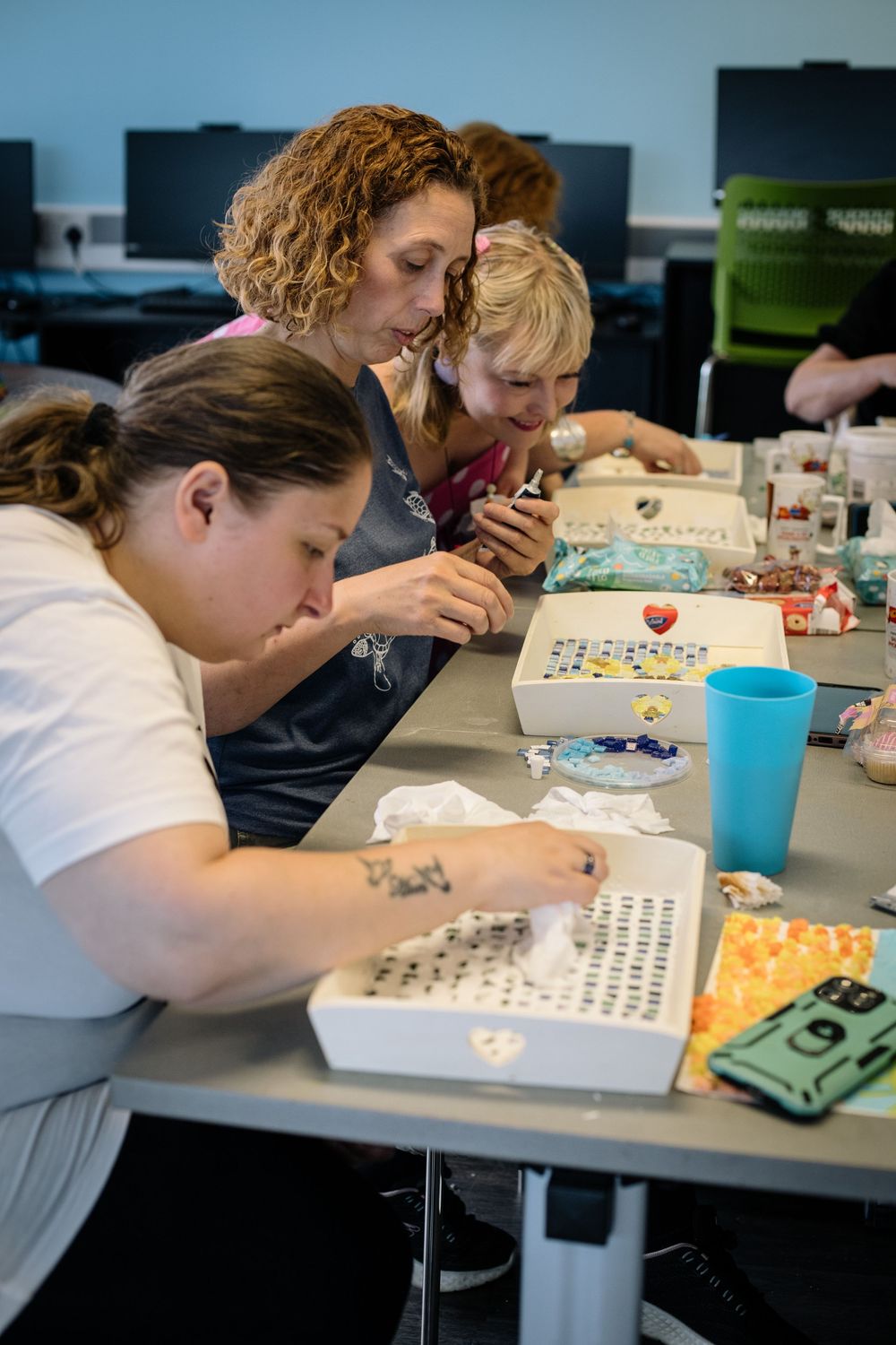 Students concentrating on a puzzle or board game activity at a classroom table with blue cups and organized materials.