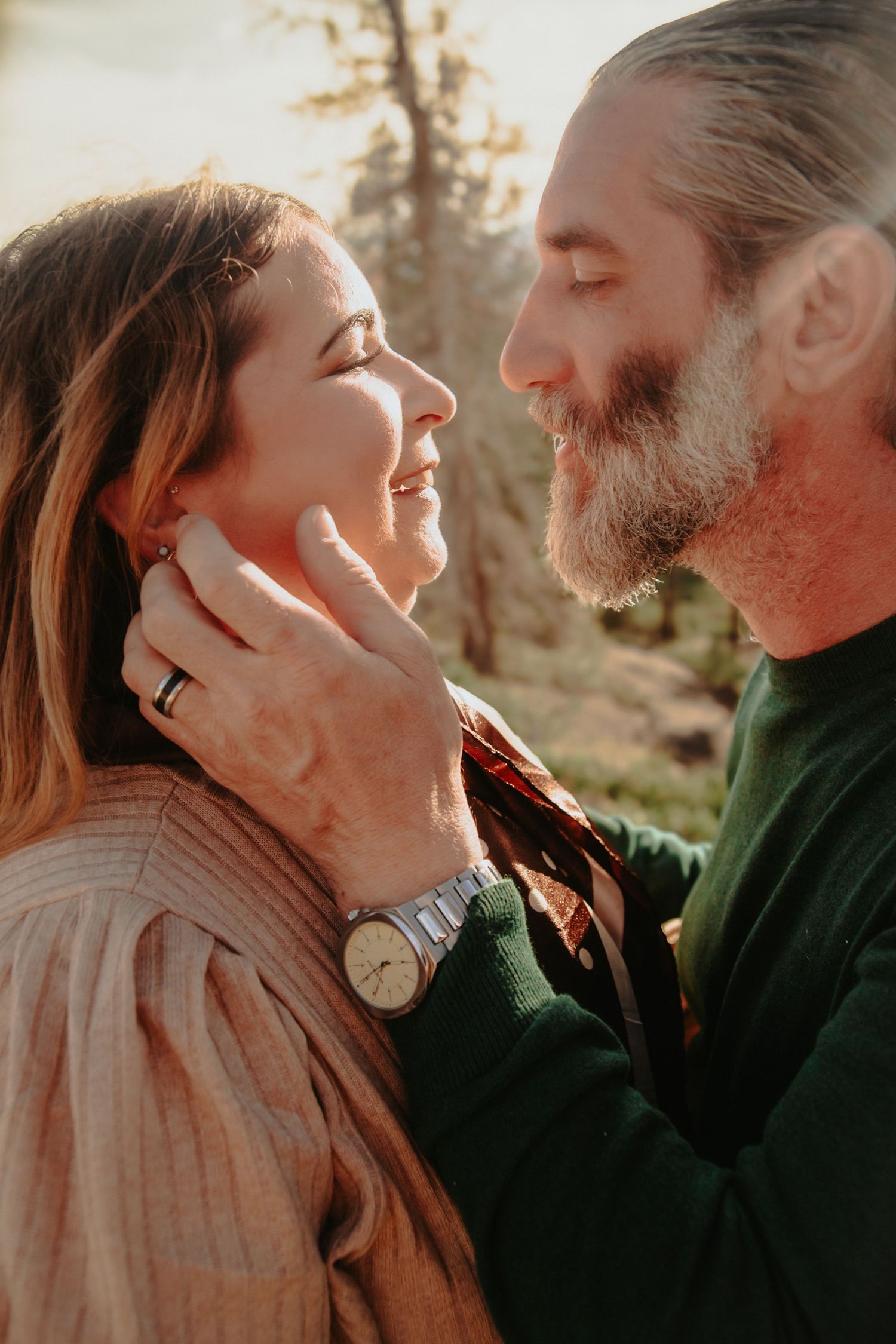 Bearded man tenderly holding woman's face in a romantic outdoor moment.