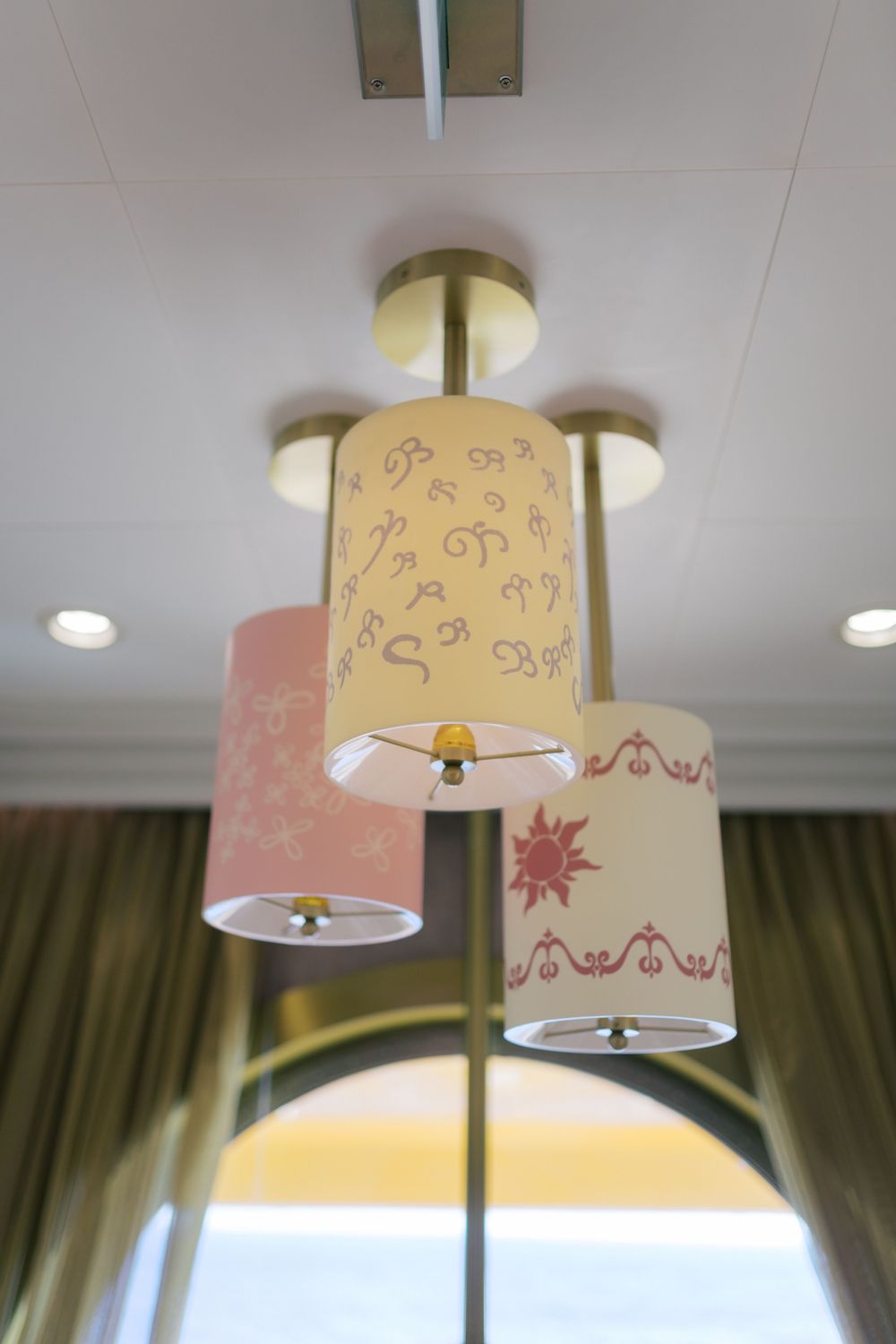 Decorative ceiling light fixture with three cylindrical lamp shades featuring elegant pink and cream floral patterns.