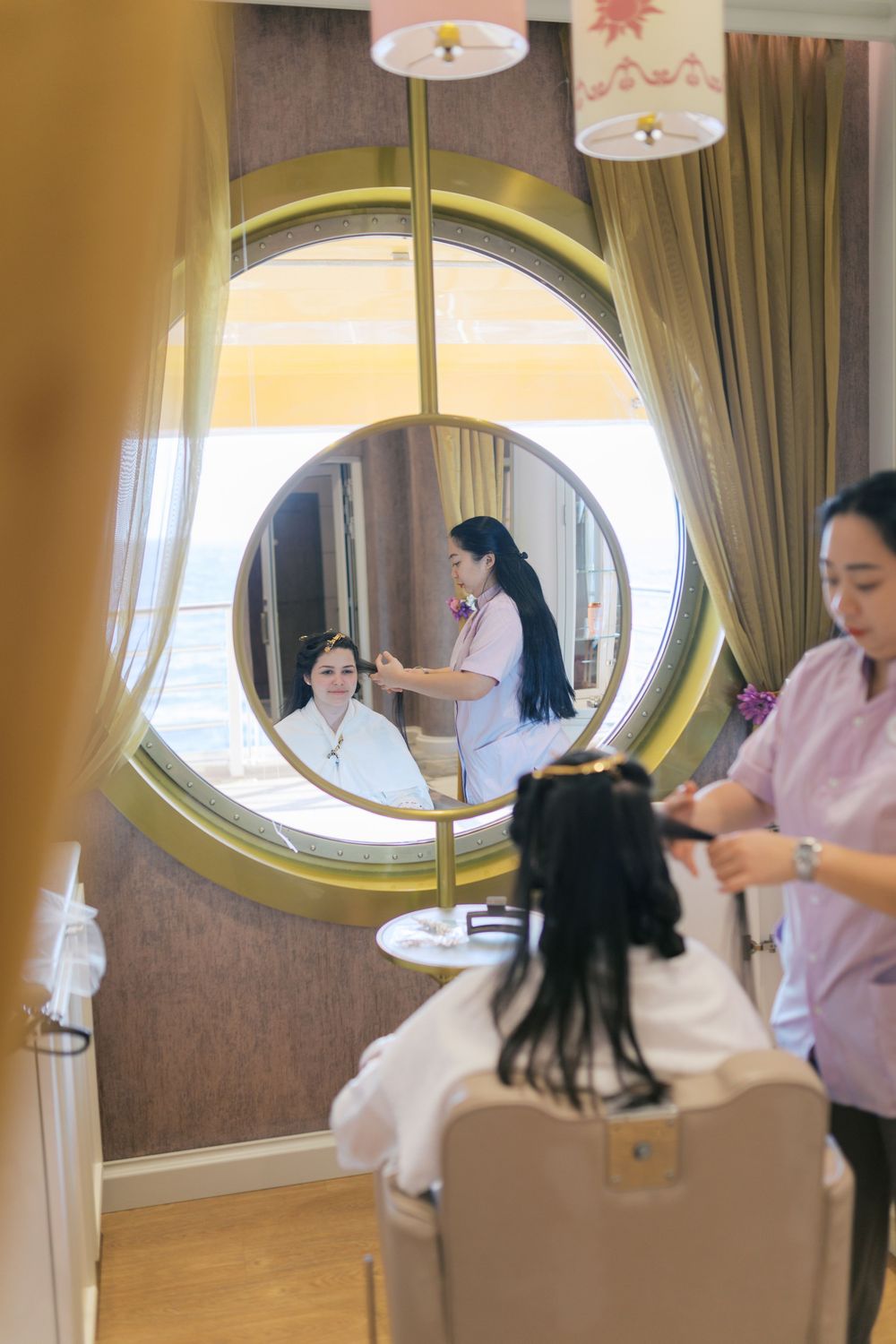 Bride getting hair and makeup done in a salon mirror on a cruise ship with ocean views.