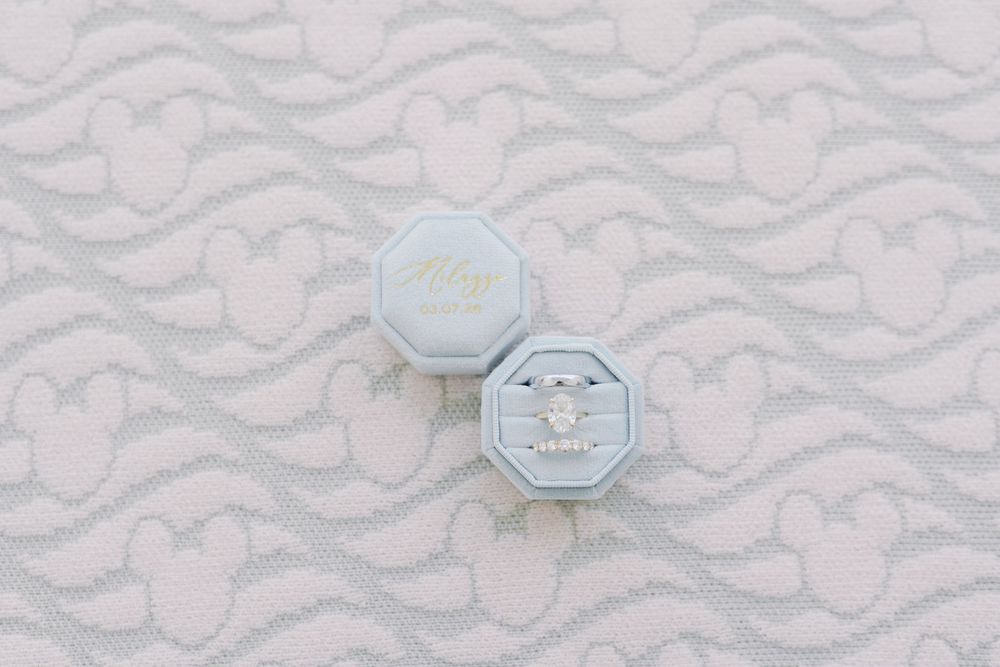 Elegant diamond engagement ring displayed in a light blue octagonal velvet ring box on a white lace background.