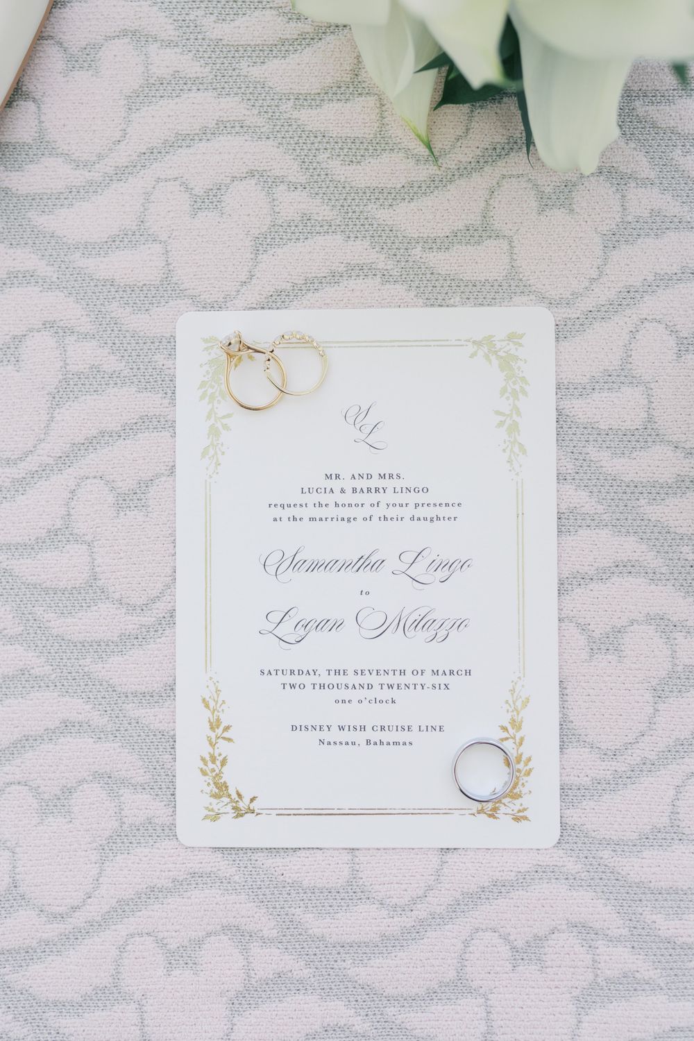 Elegant wedding invitation with gold floral details, rings, and calligraphy script on a Disney Wish Cruise Line.