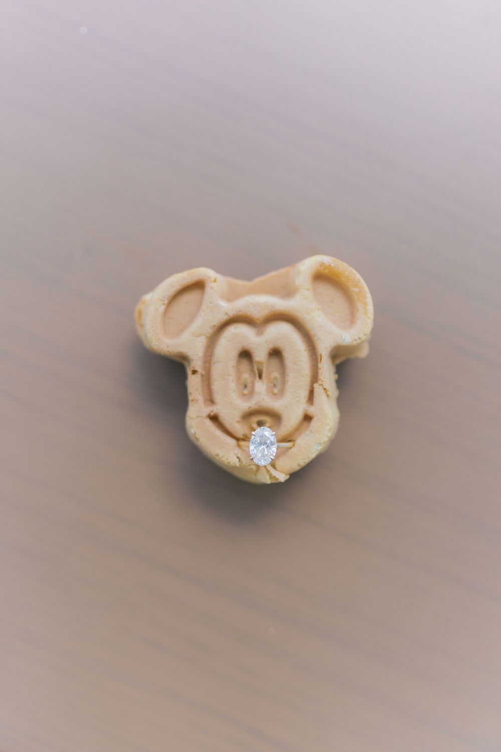 Mickey Mouse shaped waffle with a diamond engagement ring placed on it as a creative proposal.