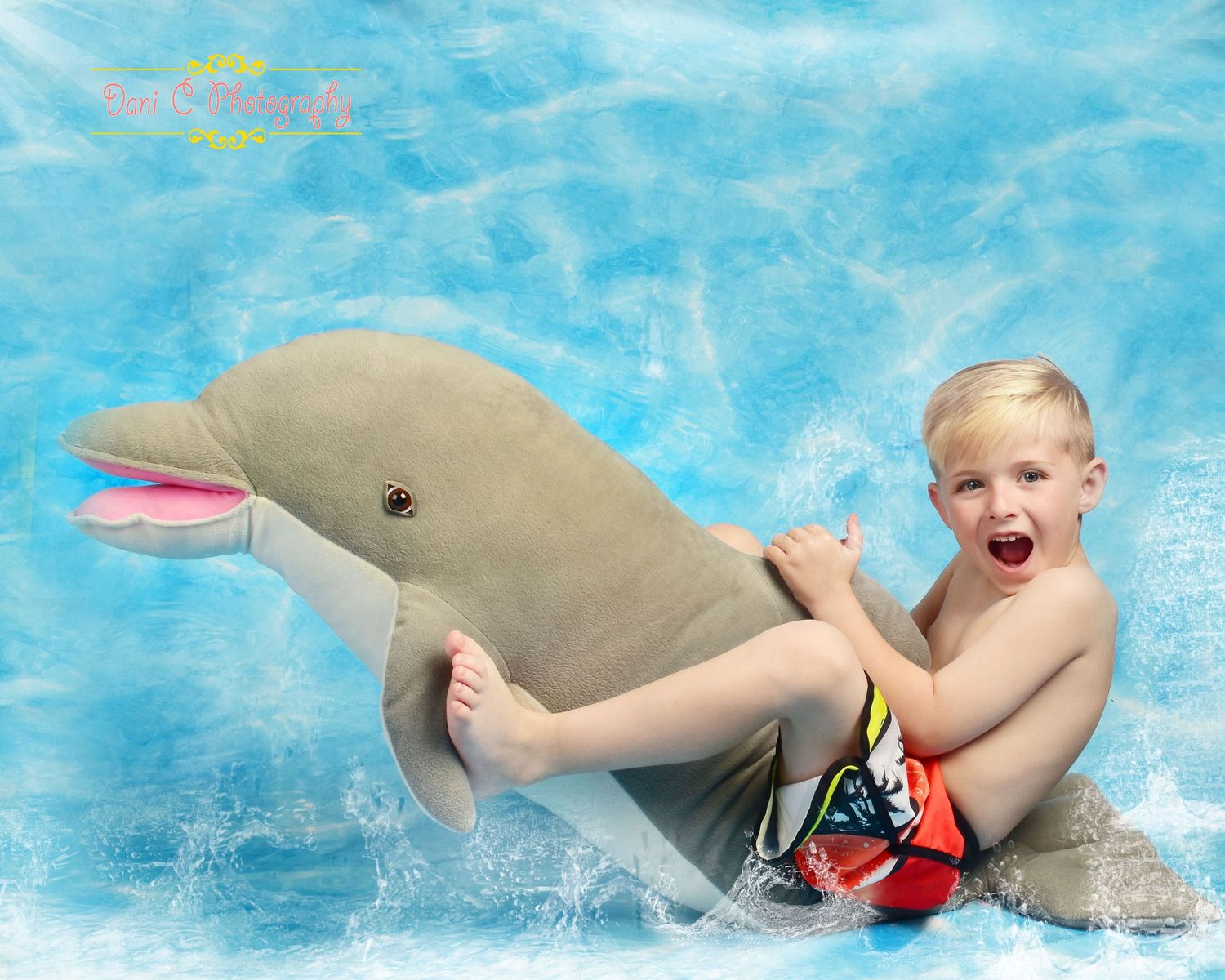 Excited young boy riding a dolphin in a bright blue pool, splashing water around them.