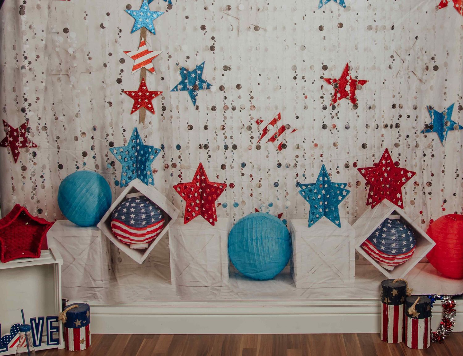 Patriotic 4th of July backdrop with red, white, blue stars, American flag pillows, and paper lanterns on white background.
